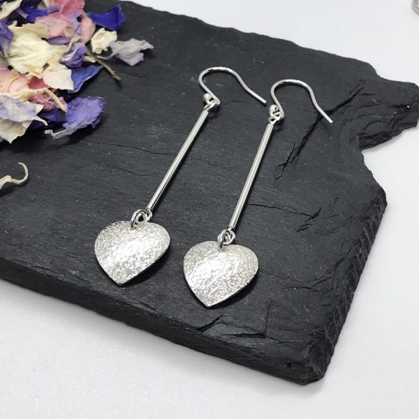 Heart dangle earrings on grey tile