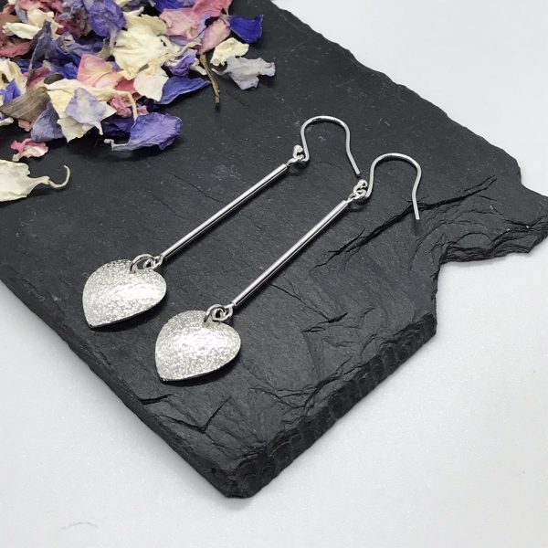 Heart dangle earrings on grey tile