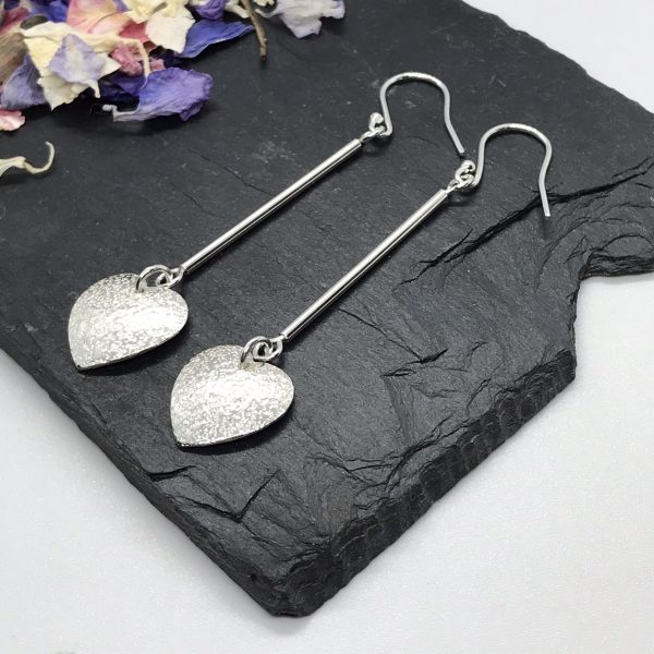 Heart dangle earrings on grey tile